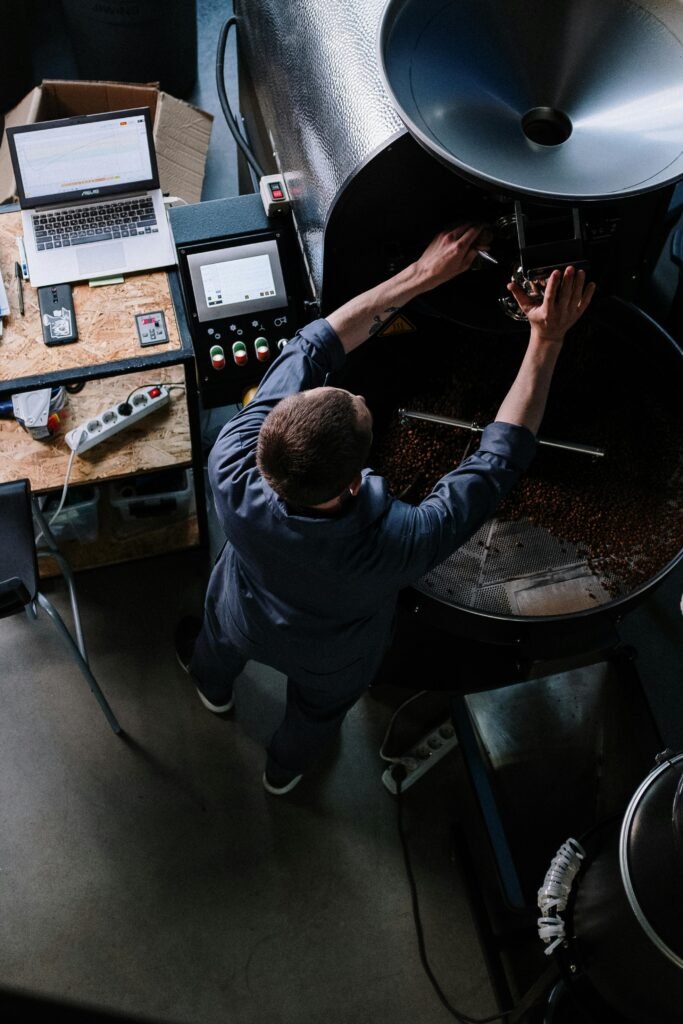 A man working with a commercial coffee bean roaster.