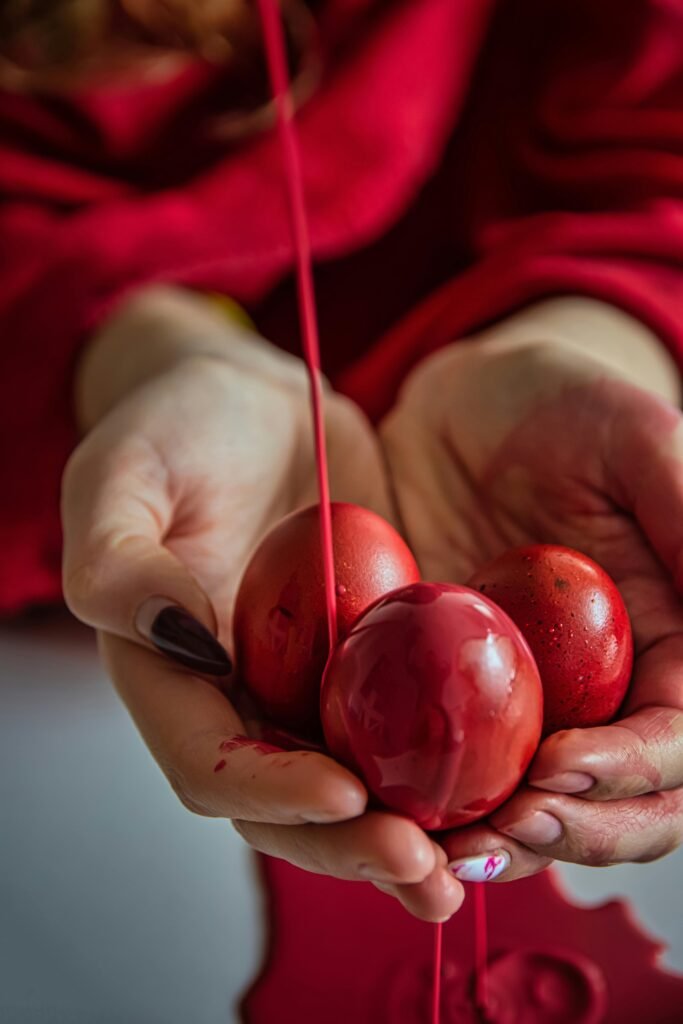 Red food coloring liquid dripping from three eggs held by two hands.