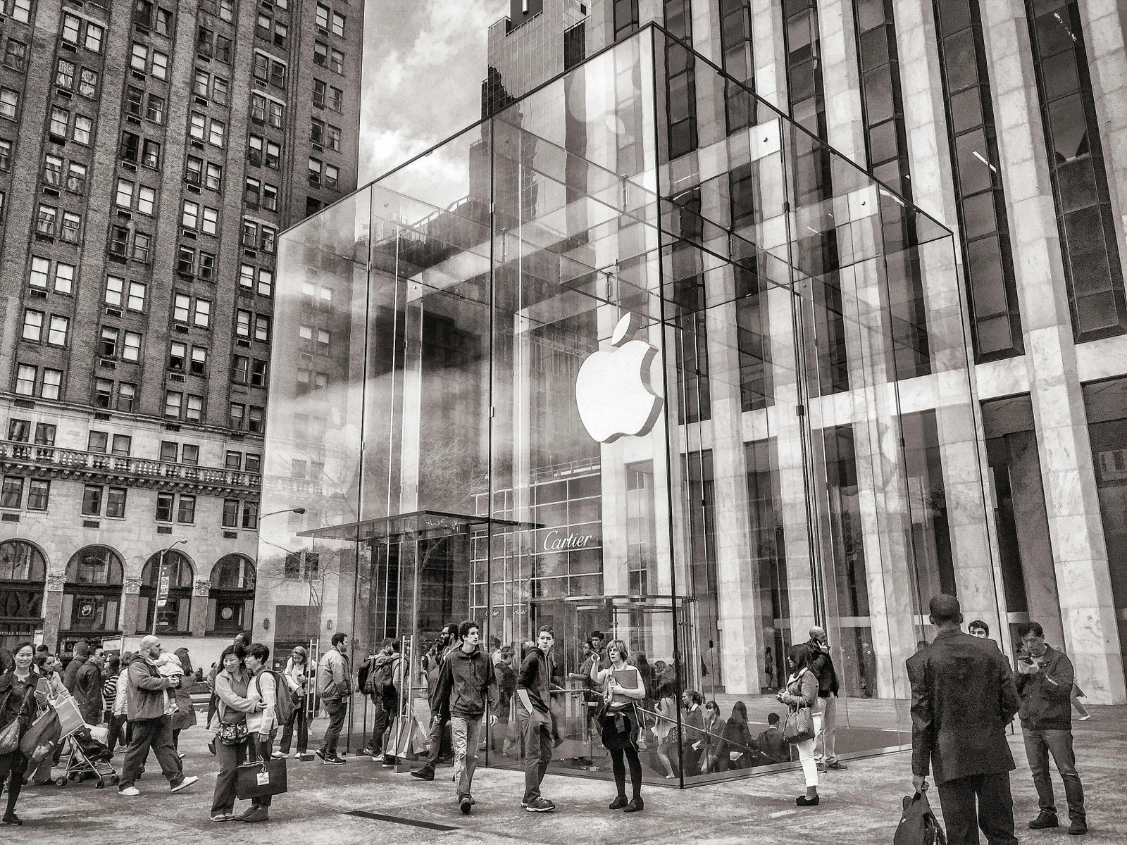 Apple store entrance with a glass structure and people gathered outside, symbolizing a customer-centric focus.