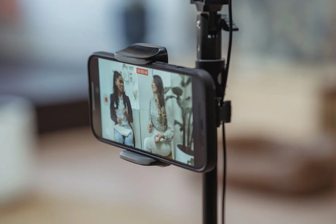 Two women discussing in front of a smartphone camera during a video recording related to "The Woke War.