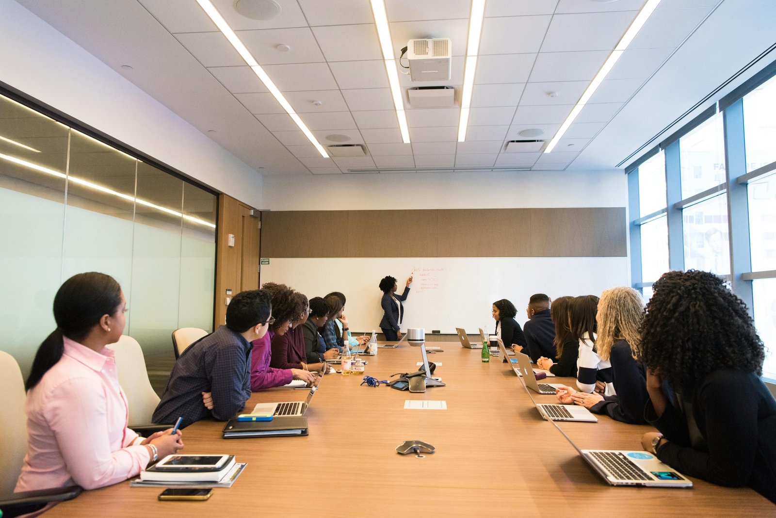 A diverse group of professionals in a meeting room discussing hiring quotas.