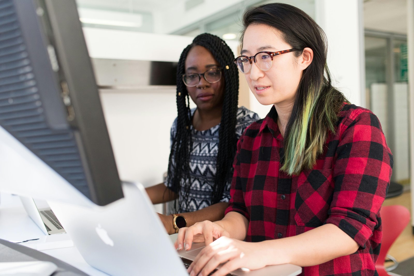 Two women collaborating on a computer, working on CRM software for small businesses.