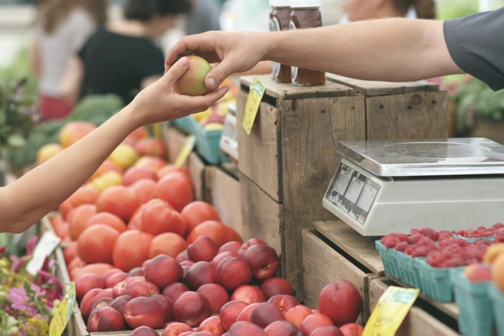 a person buying fruits at a market - people shopping at a market - a group of people walking in a busy area - Consumer sovereignty and the ethics of recognition