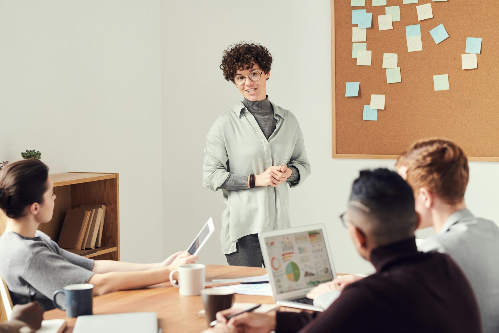 woman talking to a group of people with post-its on a board - how to scale a business quickly