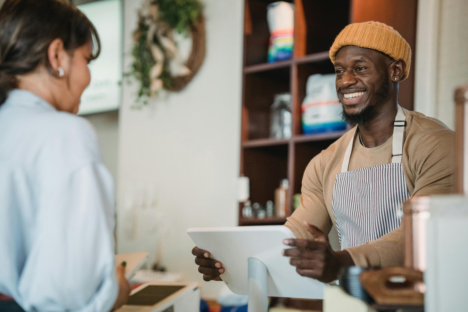 Smiling barista interacting with a customer, highlighting the importance of maintaining good relationships with customers.