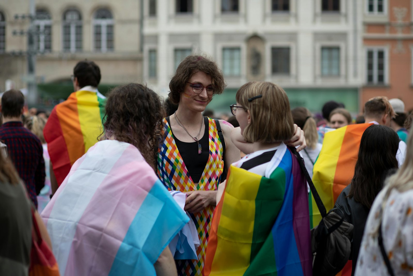 People at an event draped in pride flags, discussing gender-neutral pronouns.