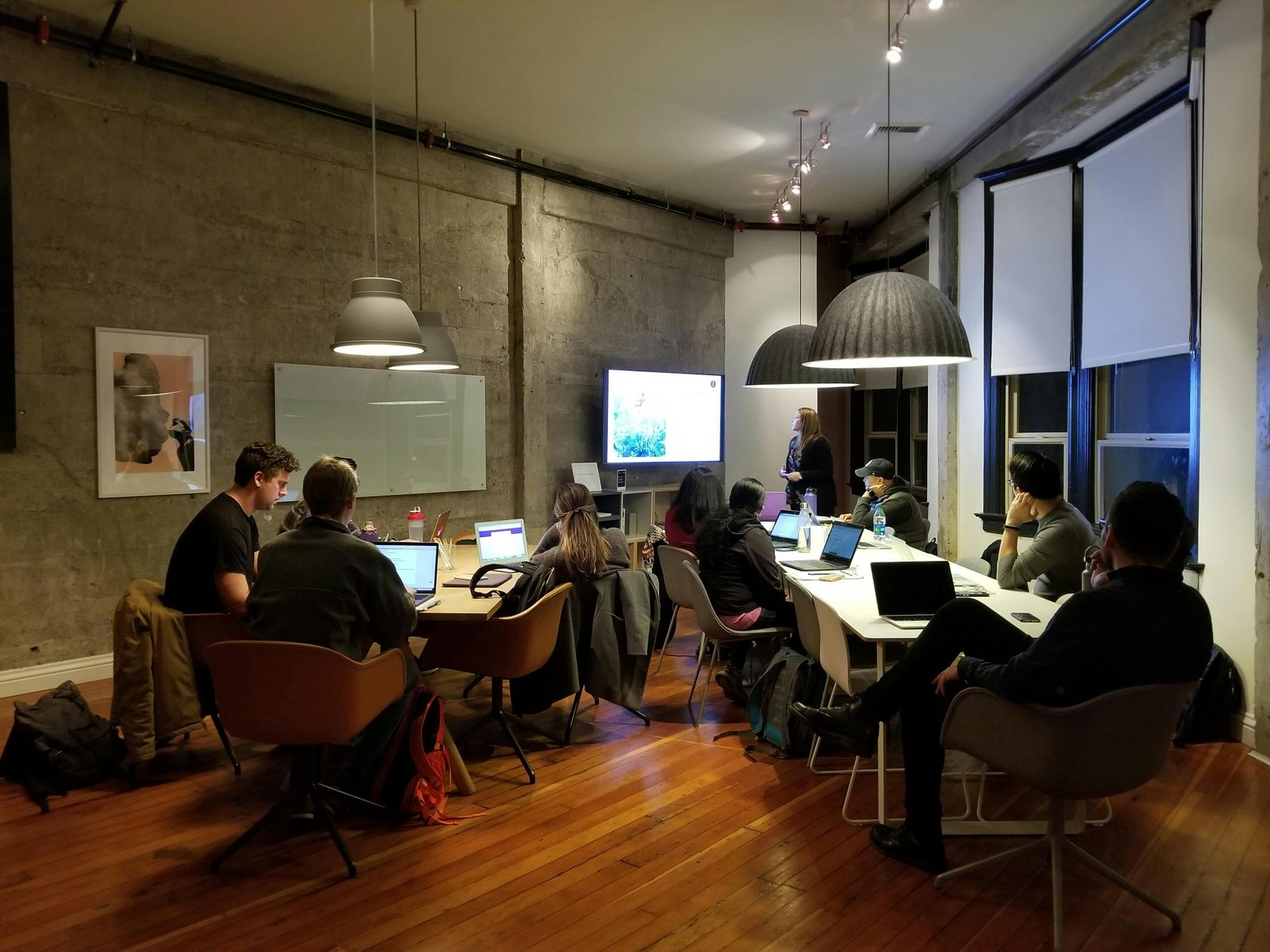 A group of people in a modern office setting using laptops and a presentation screen, illustrating the technology needs of small businesses.