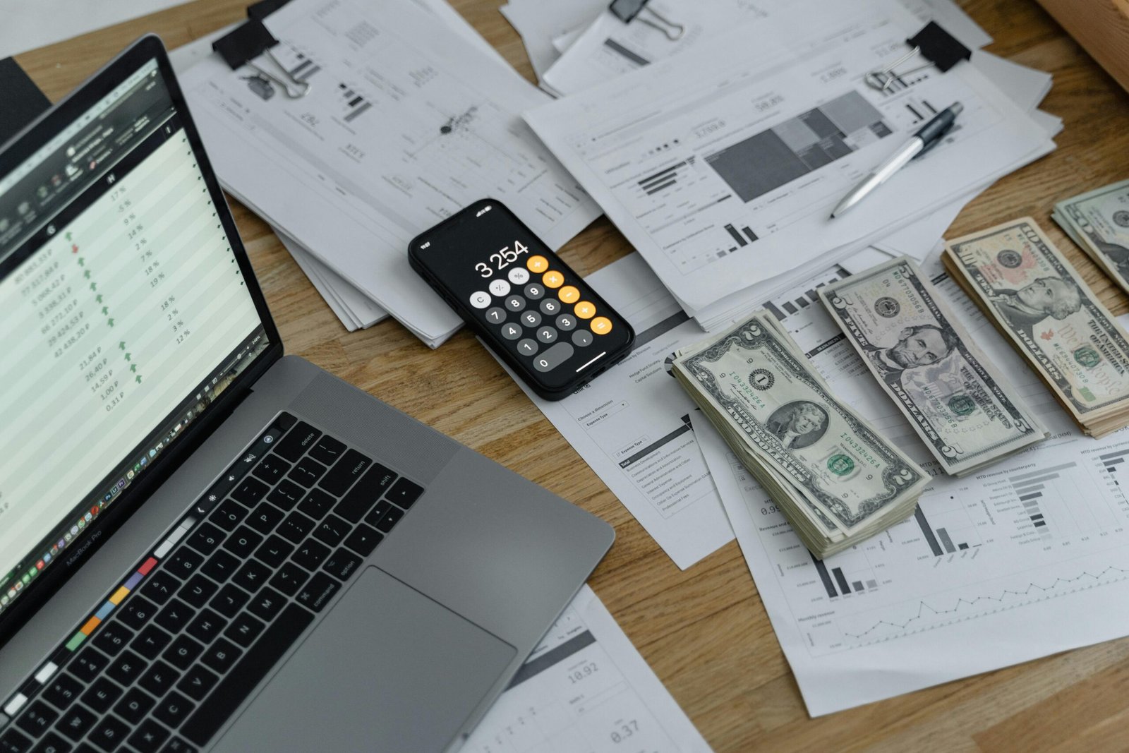 laptop, calculator, cash, and documents - how to handle cash in a small business