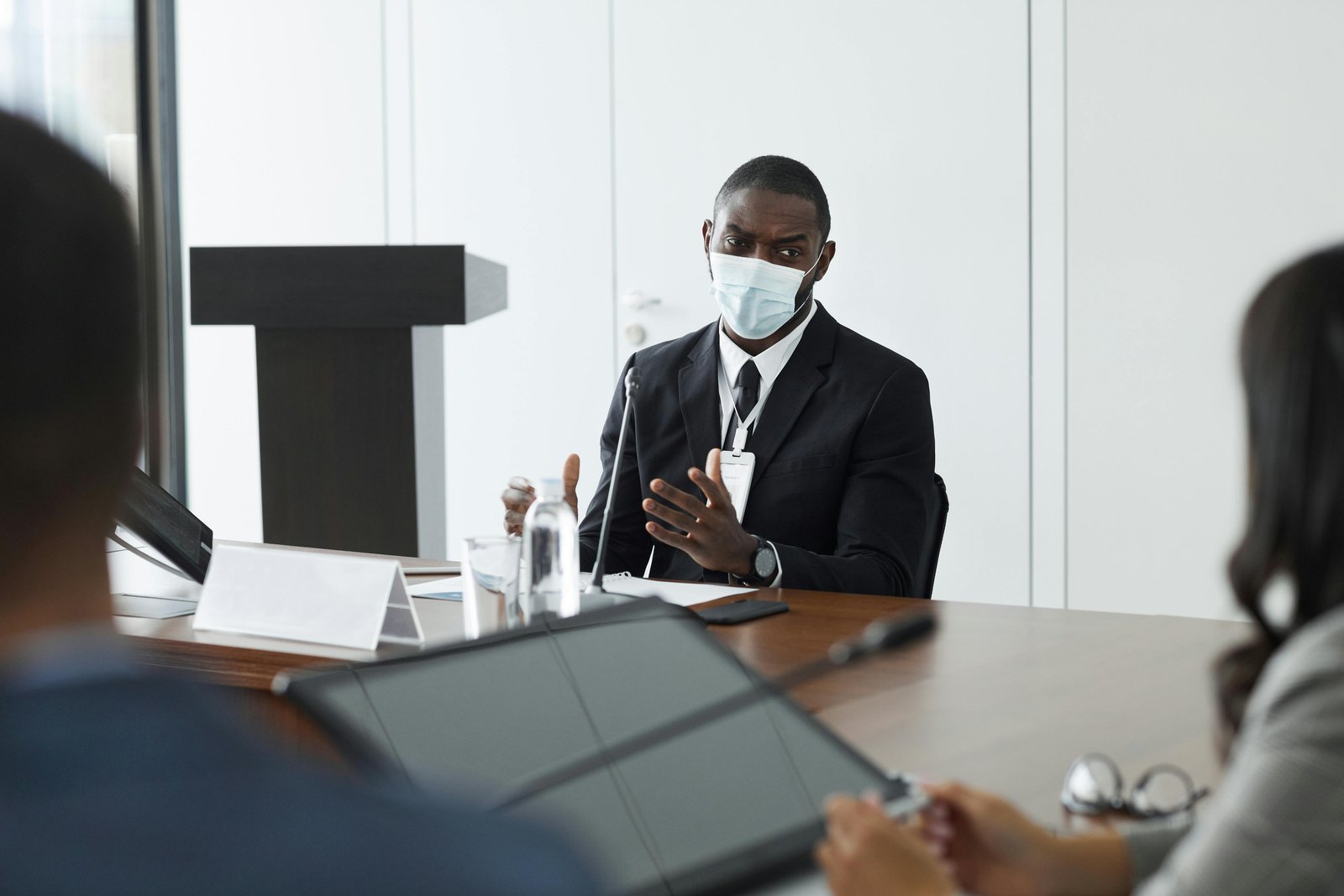 Man in a mask speaking at a meeting about the 'Woke vs. Anti-Woke Debate.'