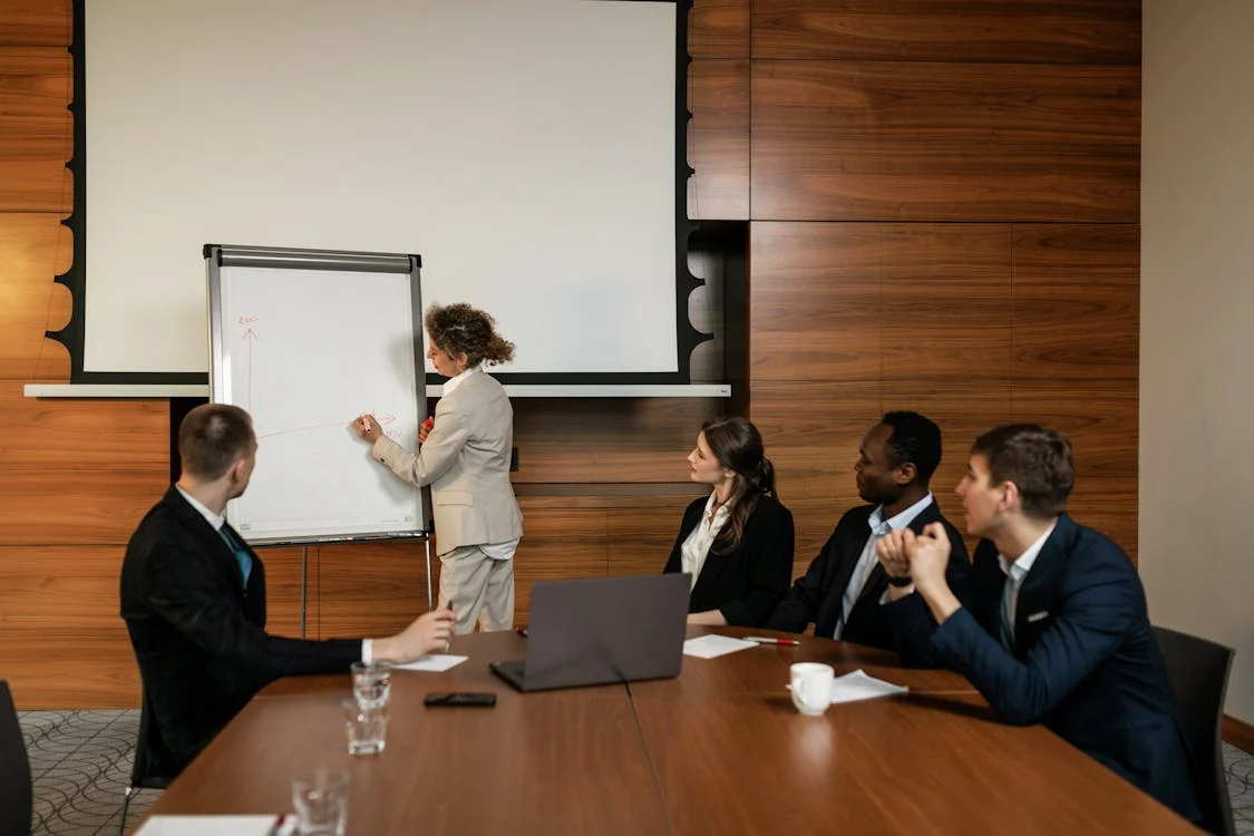 Presenter explaining a chart to a team during a 'Risk Management vs Risk Assessment' discussion.