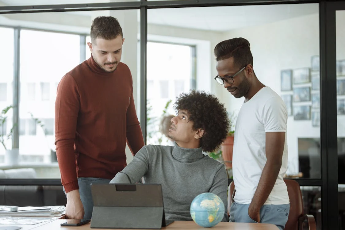 Three colleagues collaborating in a modern office, representing Global Cross-Functional Teams.