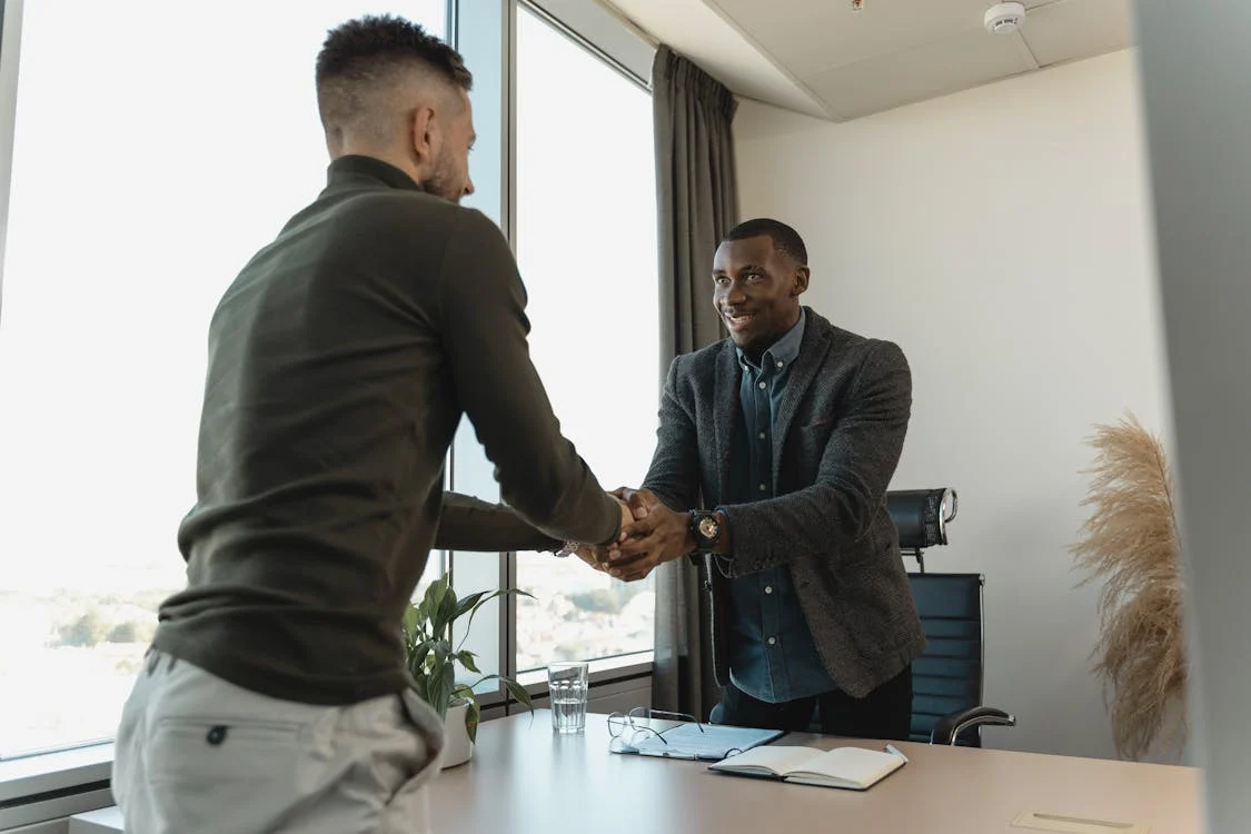 Two professionals shaking hands in an office, representing Equal Opportunity Jobs.