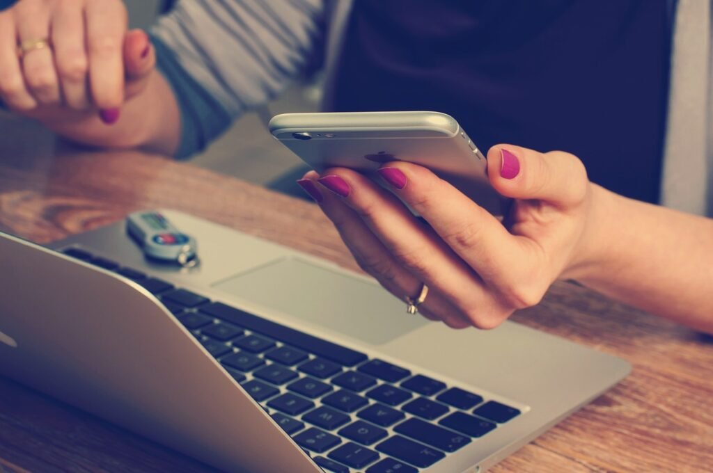 a woman holding a phone in front of a laptop - good corporate governance