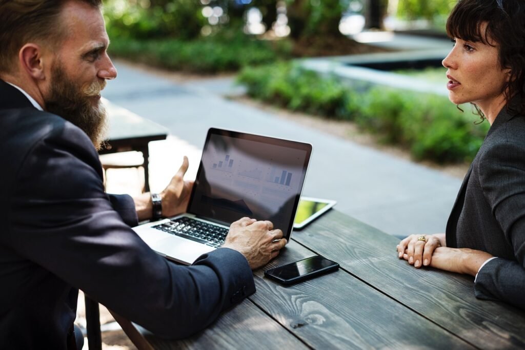 a man and woman sitting at a table with a laptop - Board of Directors and Corporate Governance