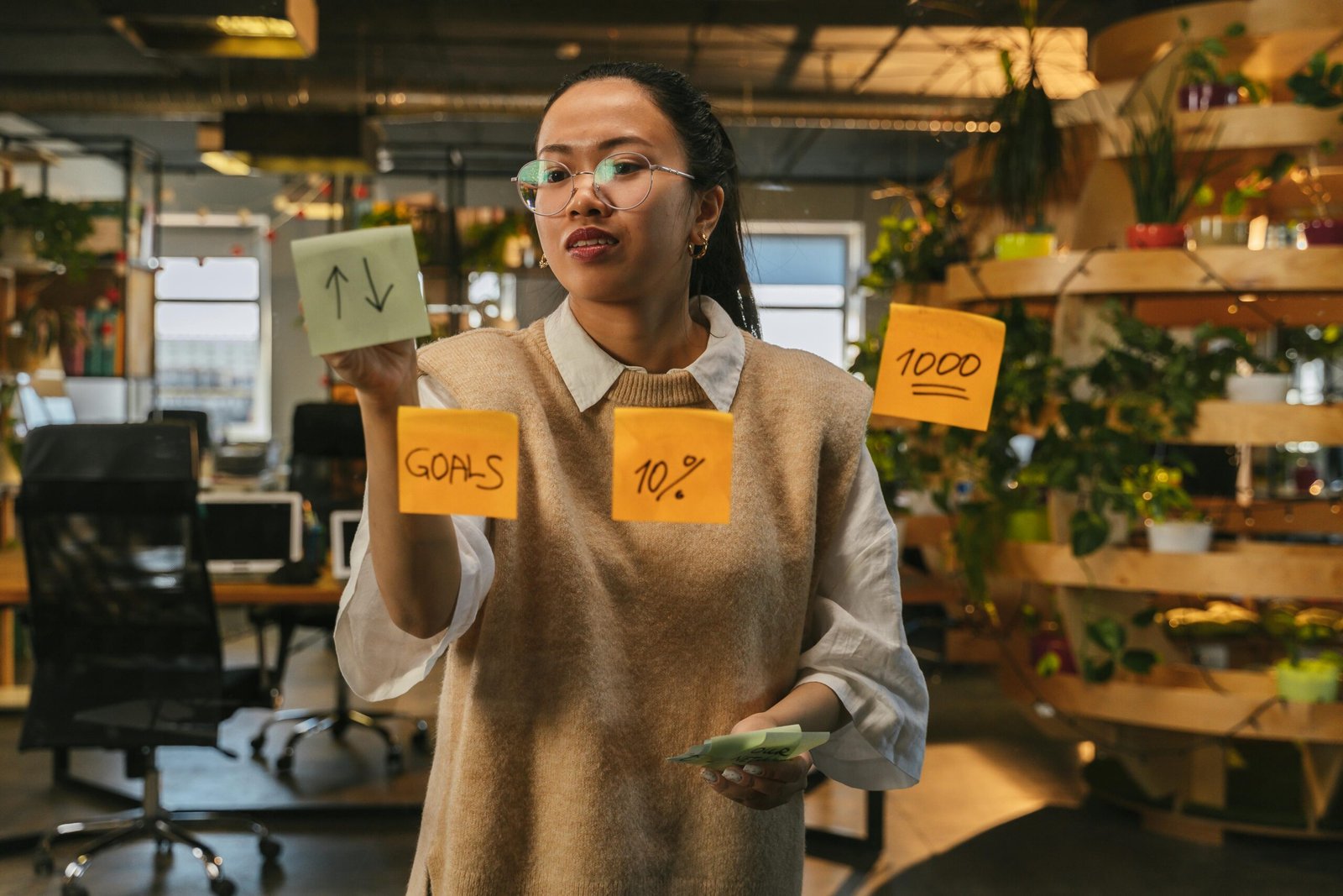 Businesswoman organizing sticky notes with 'Small Business Strategic Planning' concepts in a modern office.