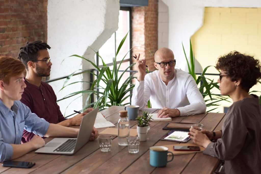 a group of people sitting around a table - Types of cross functional teams