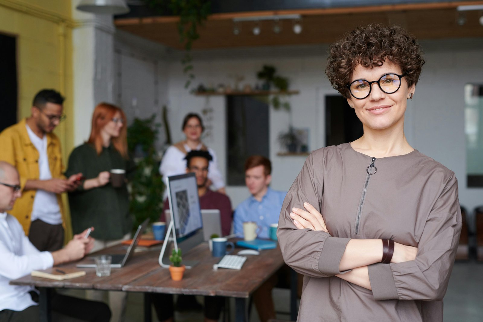 Confident woman in front of diverse team, symbolizing an Equal Opportunity Employer.