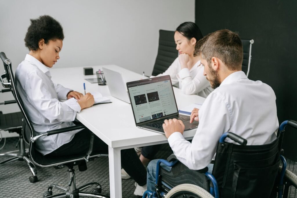 a group of people sitting at a table with a laptop - a man sitting at a desk with two computer monitors - market entry and expansion