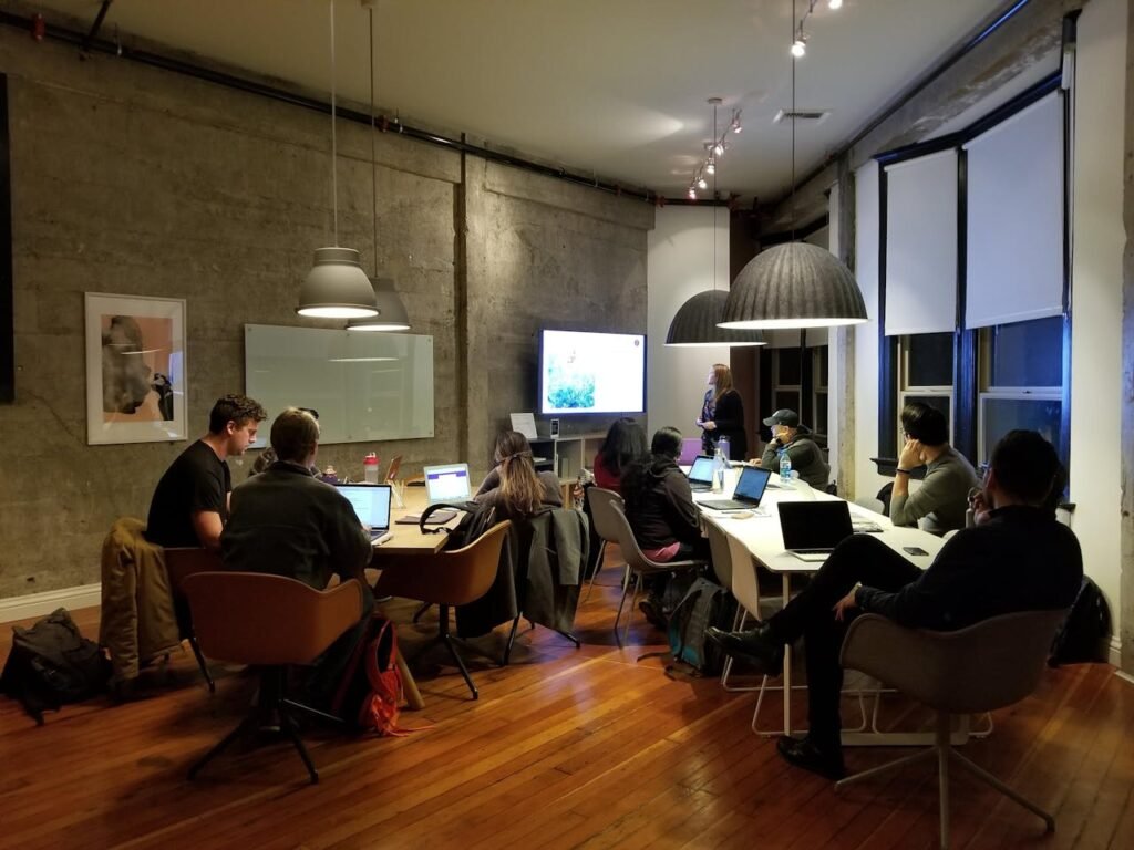 a group of people sitting at tables with laptops - compliance risk management