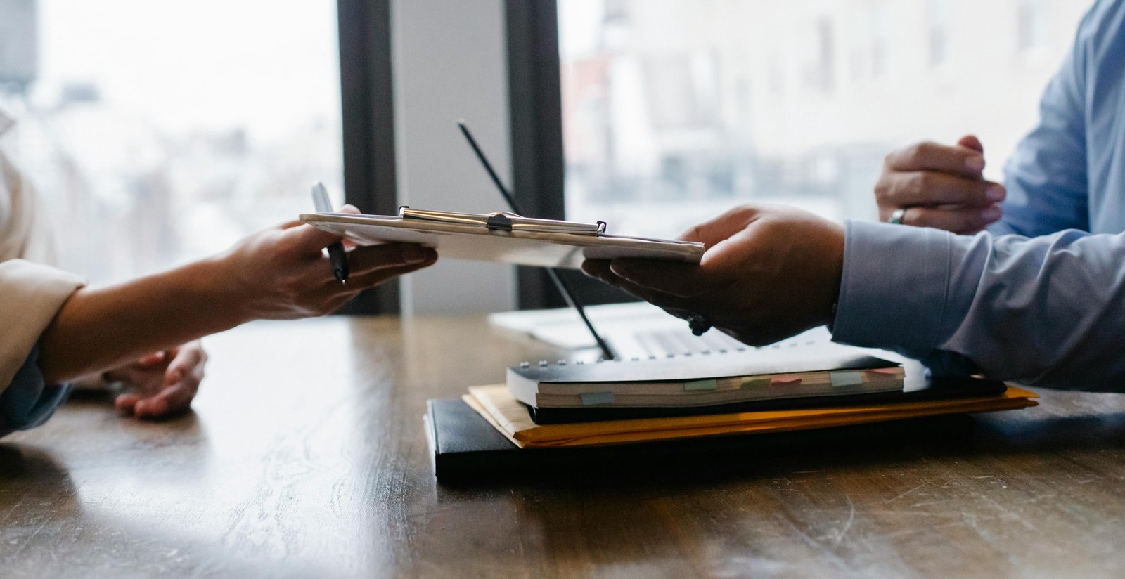 Two professionals exchanging documents, representing Equal Employment Opportunity Laws.