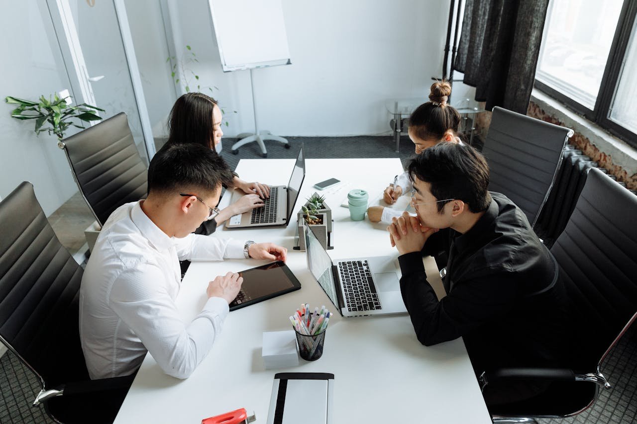 a group of people sitting at a table with laptops