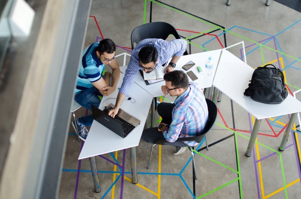 a group of men sitting around a table with laptops - strategic workforce planning