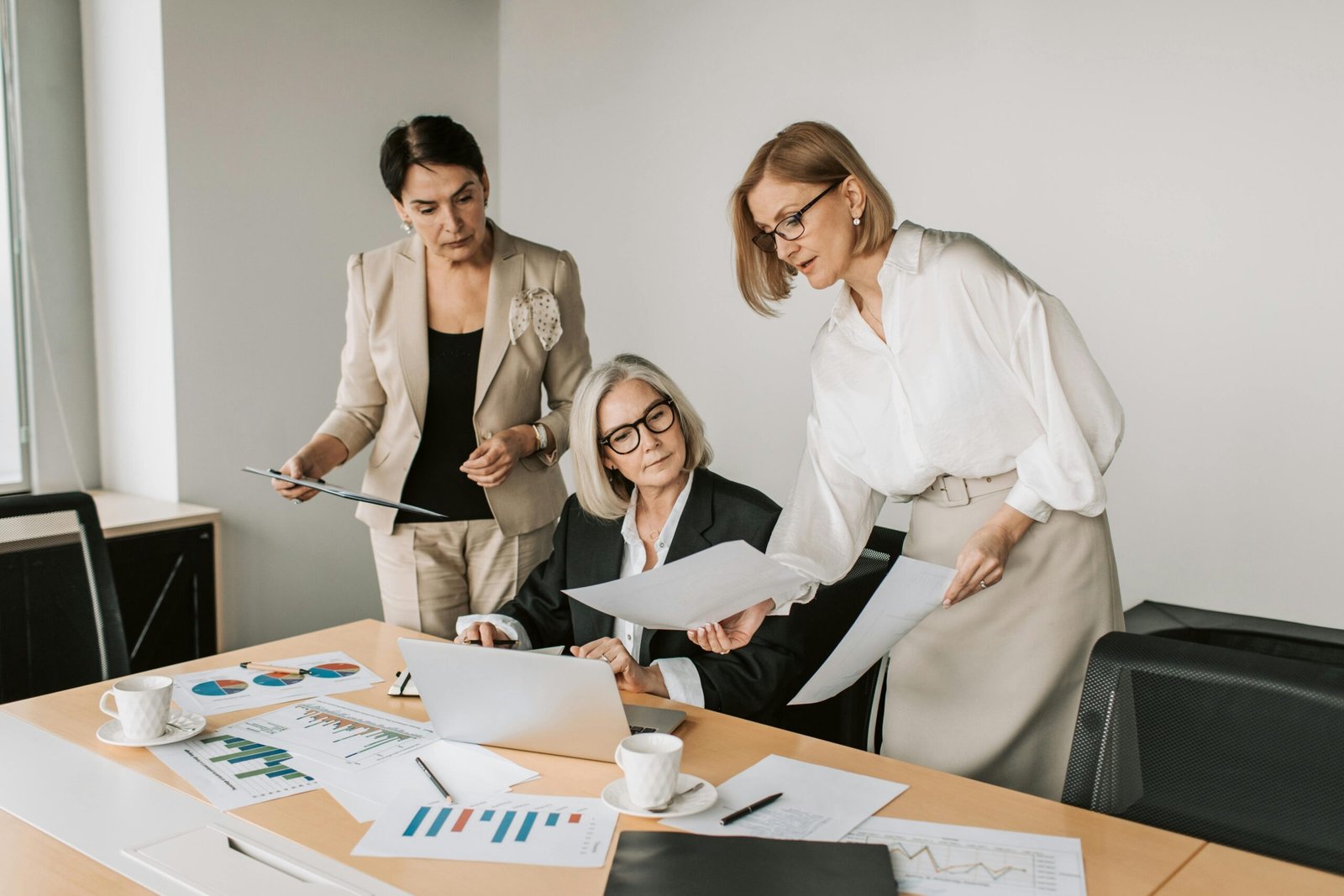 Three women collaborating on corporate strategic planning documents in an office.