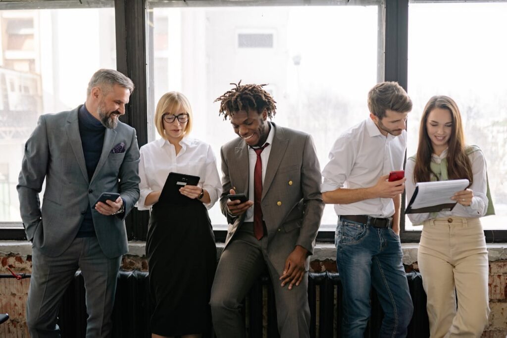 a group of people looking at their phones - Cross Functional Knowledge Sharing