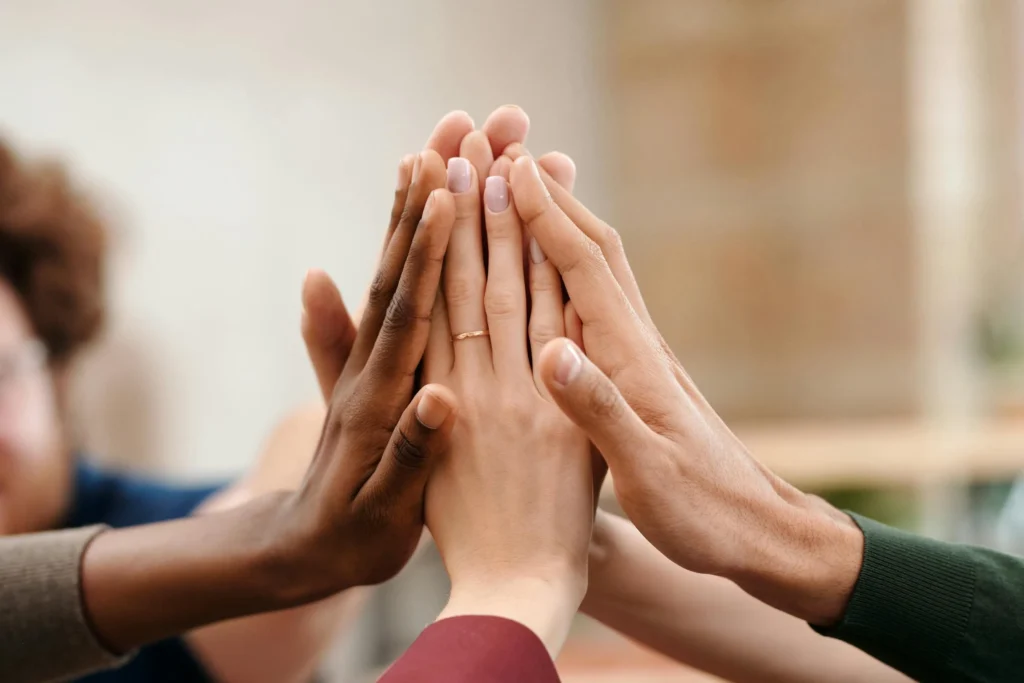 a group of people putting their hands together - do government agencies get tax cuts for dei