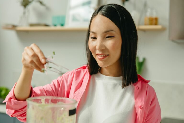 Woman in pink shirt smiling with a herb in hand