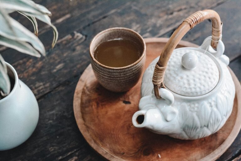 White teapot and a cup of tea on a tray