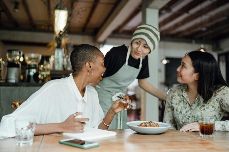Two women in a cafe being attended to by a woman