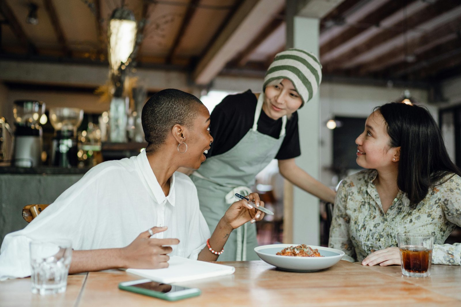 Two women in a cafe being attended to by a woman