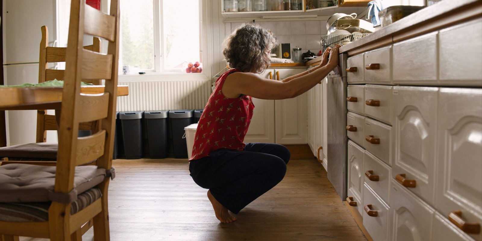 Woman squatting in front of a dishwasher
