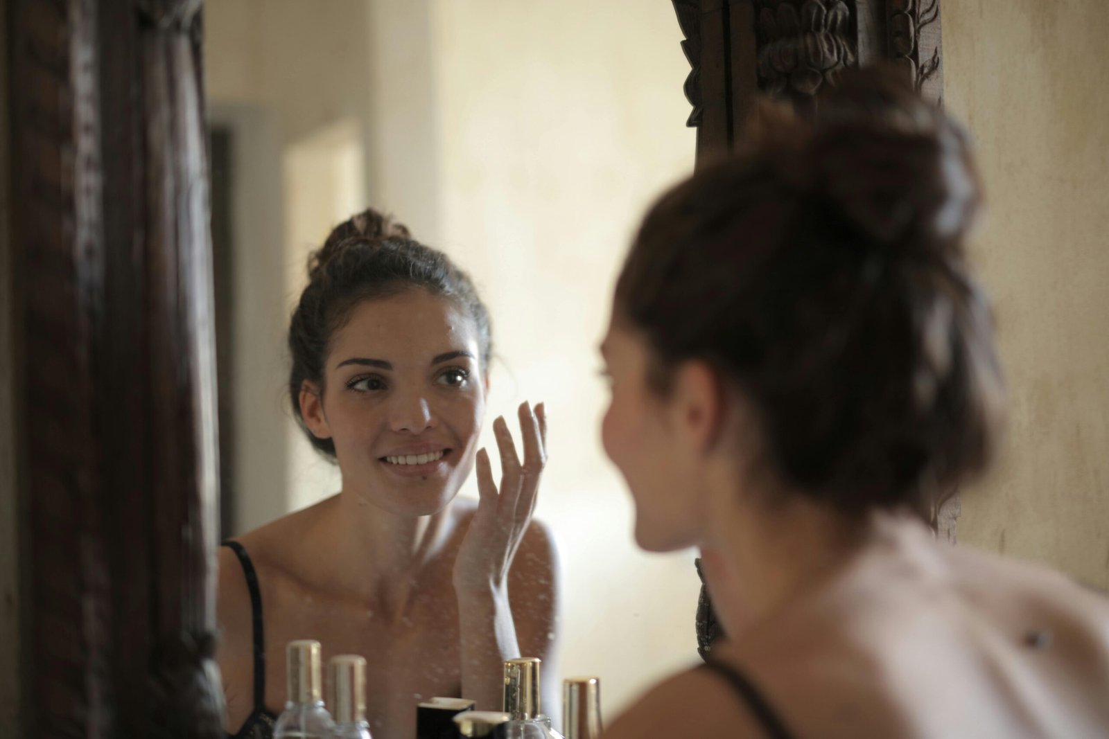Woman doing skincare in front of a mirror