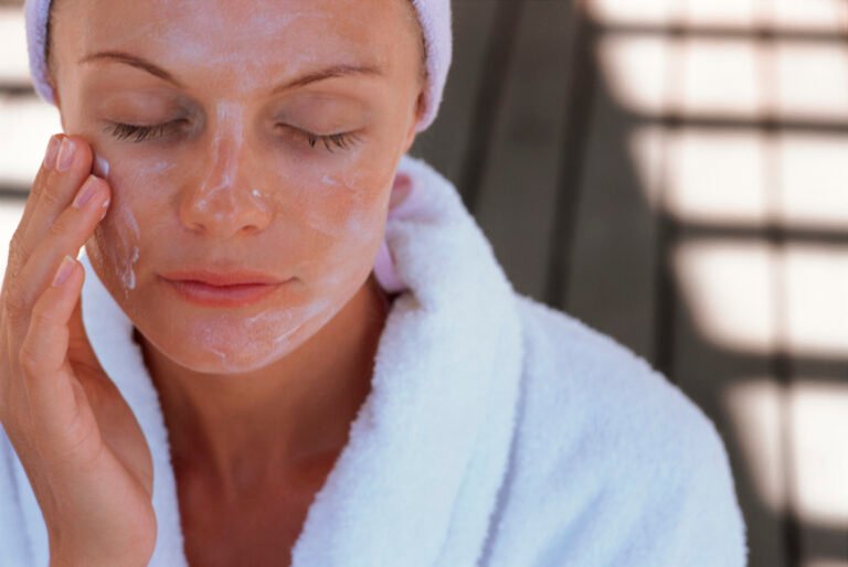 Woman putting lotion on face outdoors