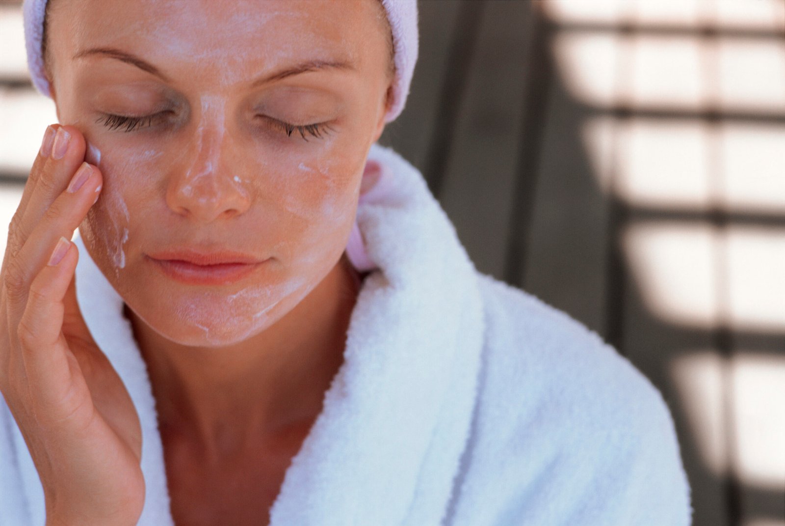 Woman putting lotion on face outdoors