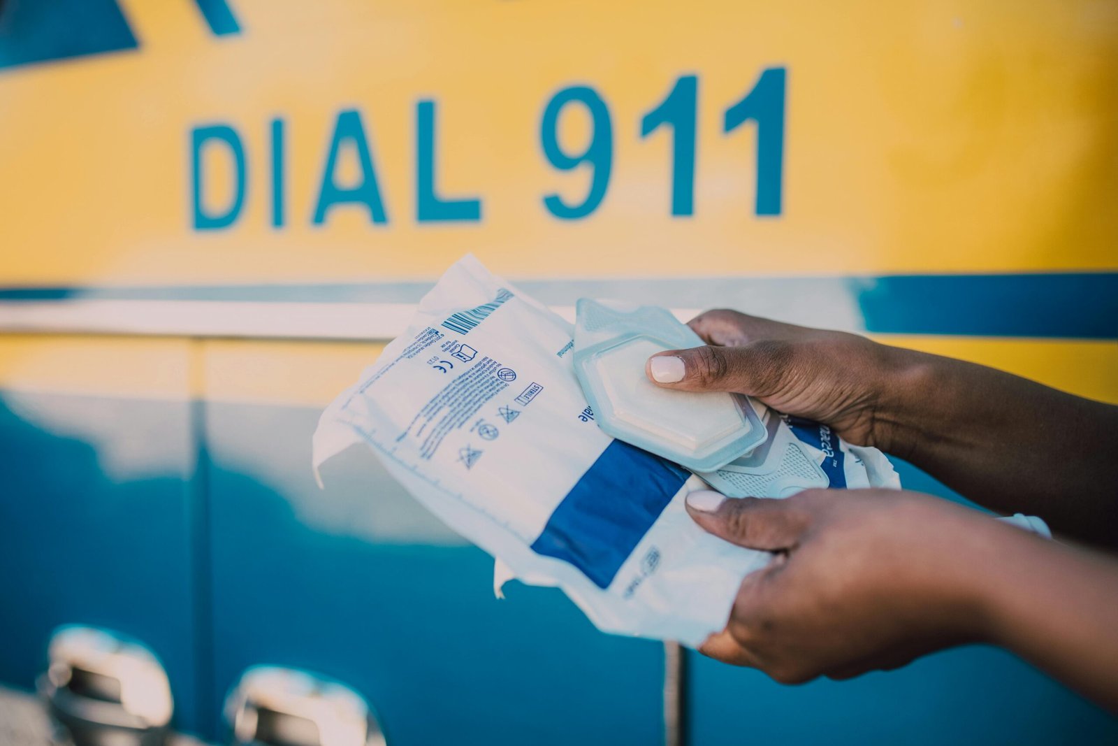Dial 911 on a yellow background and a hand holding packages