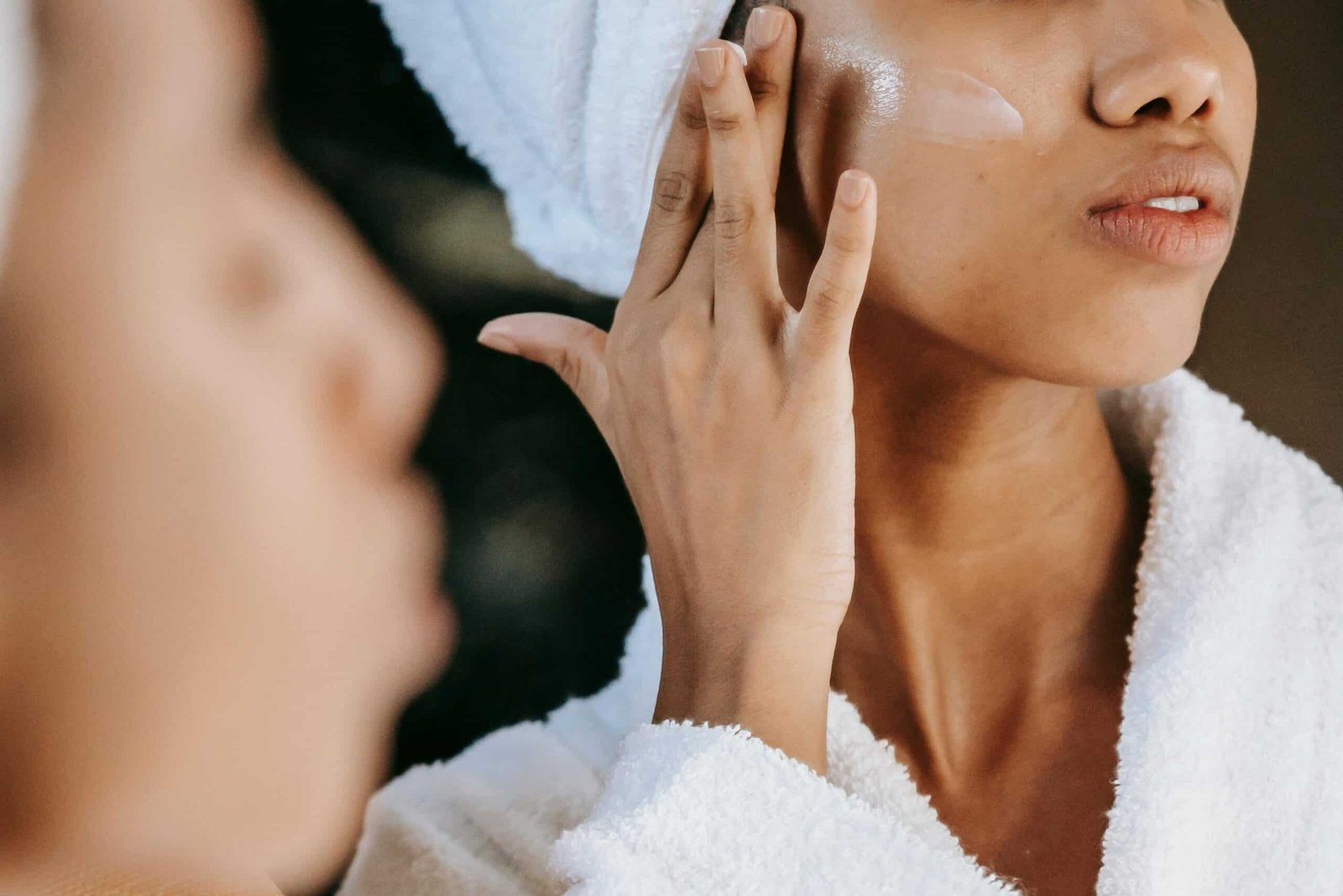Woman in the mirror applying lotion to face