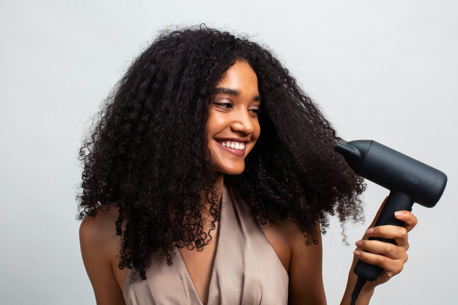 Woman with curly hair using a blow dryer