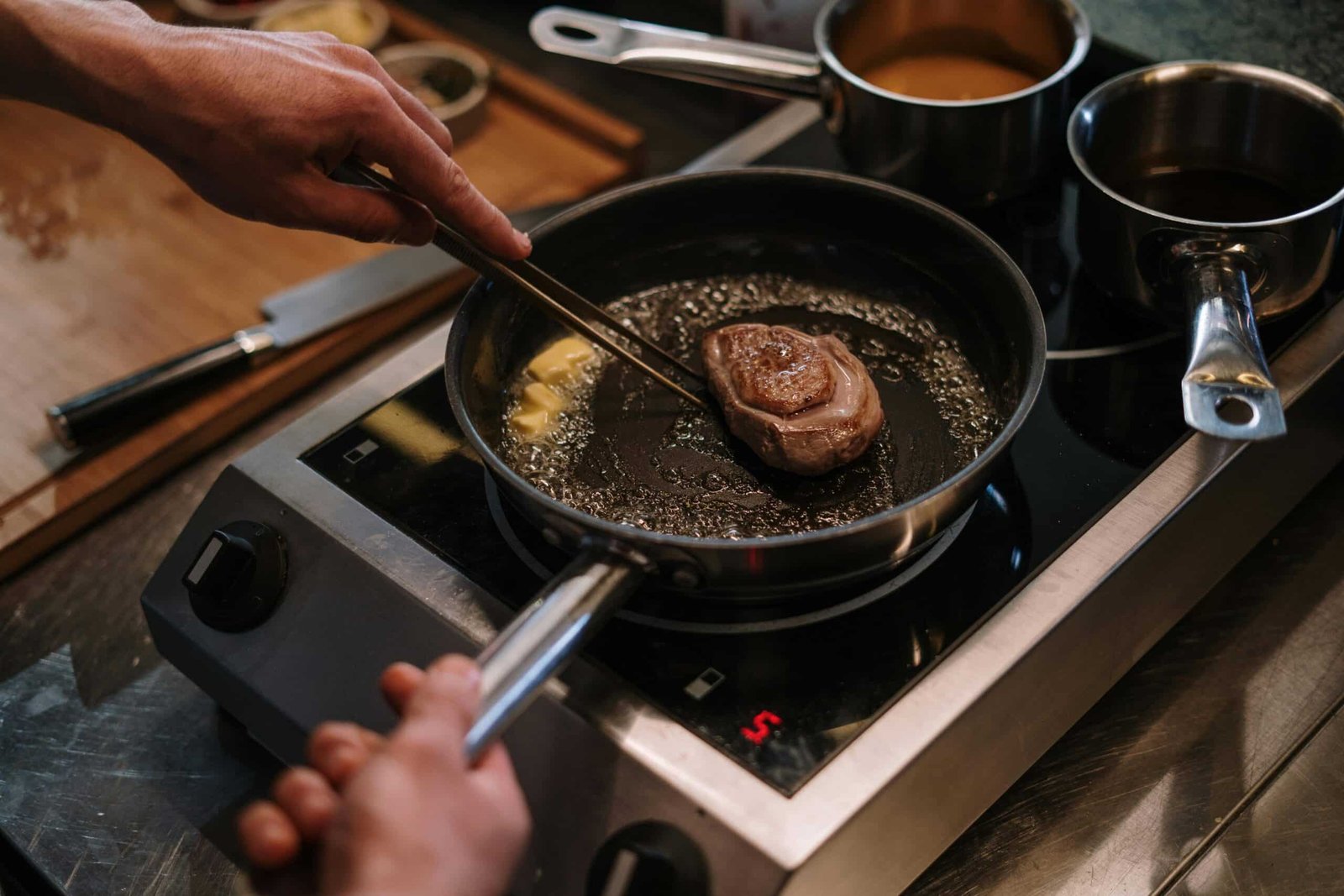 Person cooking steak on a pan