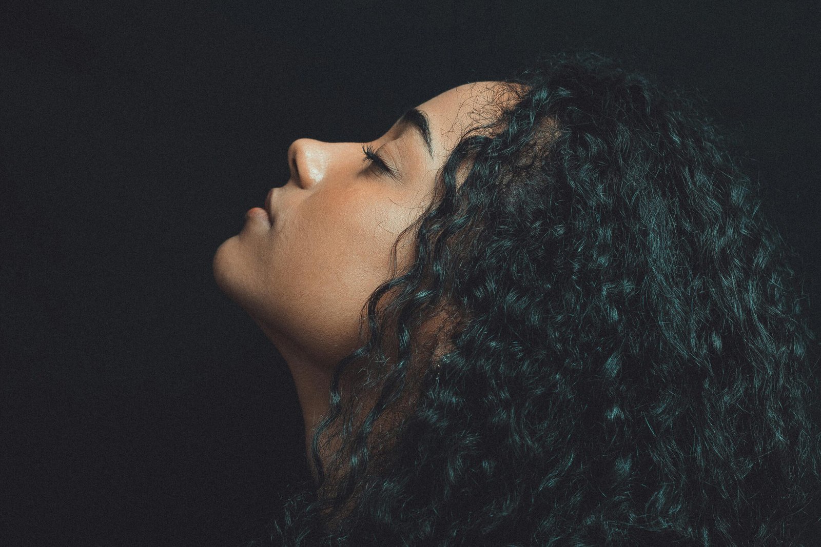Curly-haired woman against a dark background