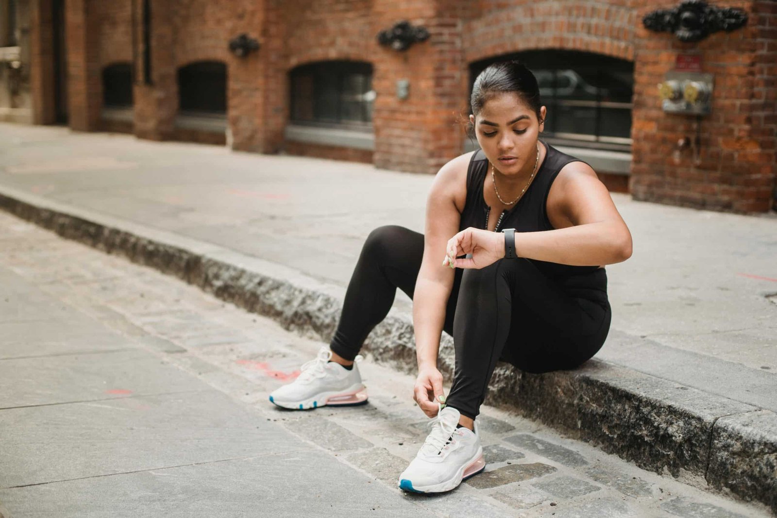 Woman in sports wear sitting on a pavement
